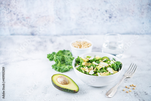 Kale avocado pine nuts cheese salad with lemon dressing in a bowl