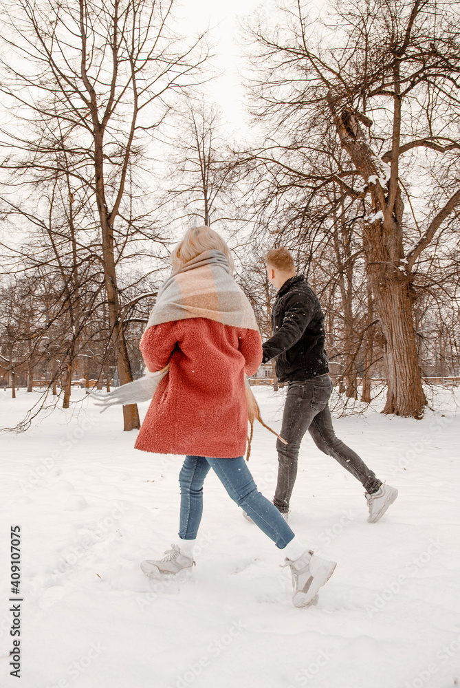 Young romantic couple is having fun outdoors in winter. Two lovers are hugging and kissing in Saint Valentine's Day. Hipster couple hugging each other in winter forest. Love story.