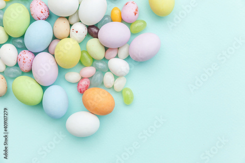 Happy Easter concept. Preparation for holiday. Easter candy chocolate eggs and jellybean sweets isolated on trendy pastel blue background. Simple minimalism flat lay top view copy space.