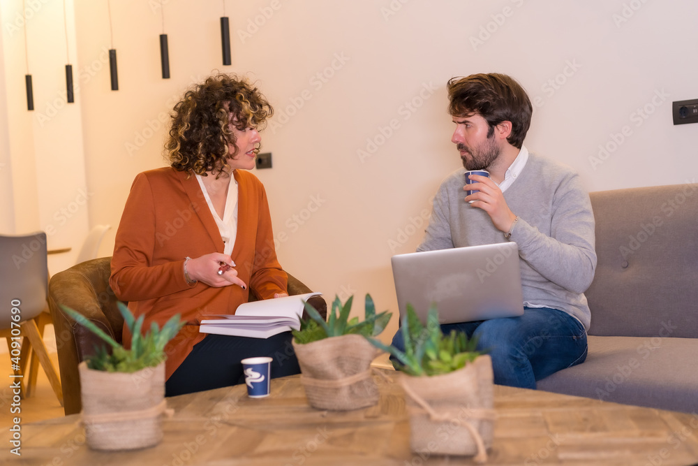 Young entrepreneurs in a business meeting on sofas with a computer and a notepad Young entrepreneurs in a business meeting on sofas with a computer and a notepad