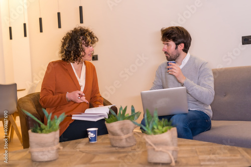 Young entrepreneurs in a business meeting on sofas with a computer and a notepad