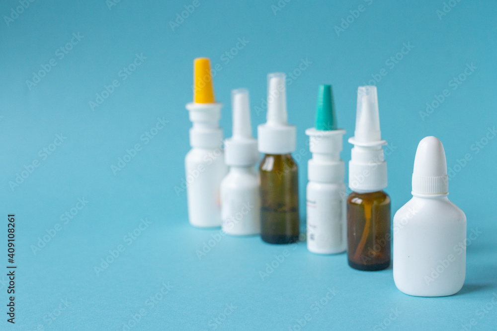 Bottles of nasal spray standing in line on blue background, medicine flat lay, treatment for colds Bottles of nasal spray standing in line on blue background, medicine flat lay, treatment for colds