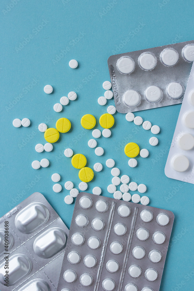White and yellow pills flat lay for blogger medicine content with copy space on blue background White and yellow pills flat lay for blogger medicine content with copy space on blue background