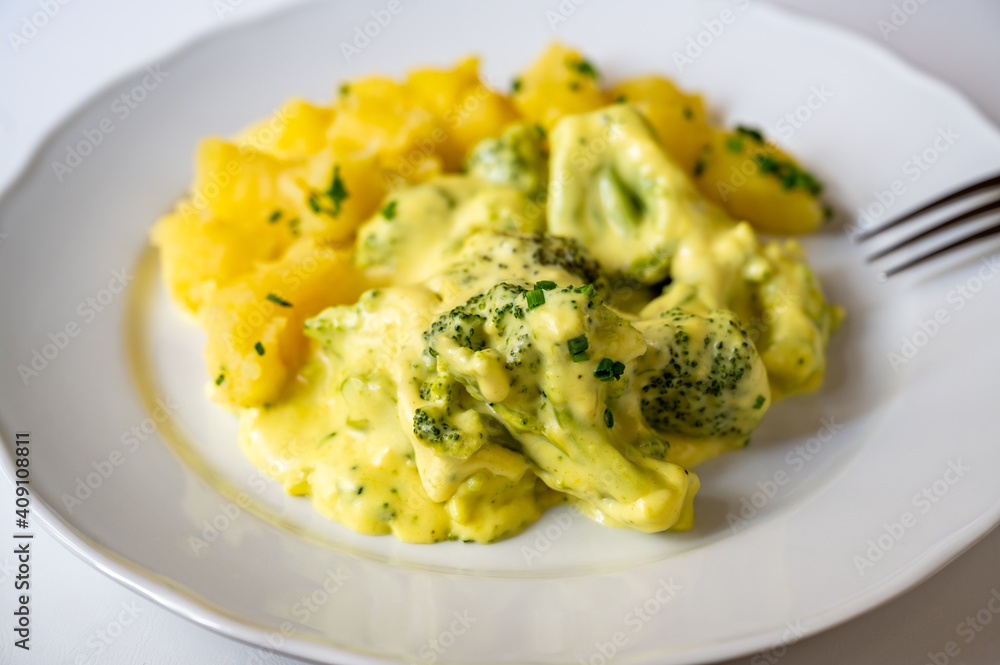 Stewed broccoli in creamy sauce with boiled potato on white plate. Stewed broccoli in creamy sauce with boiled potato on white plate.
