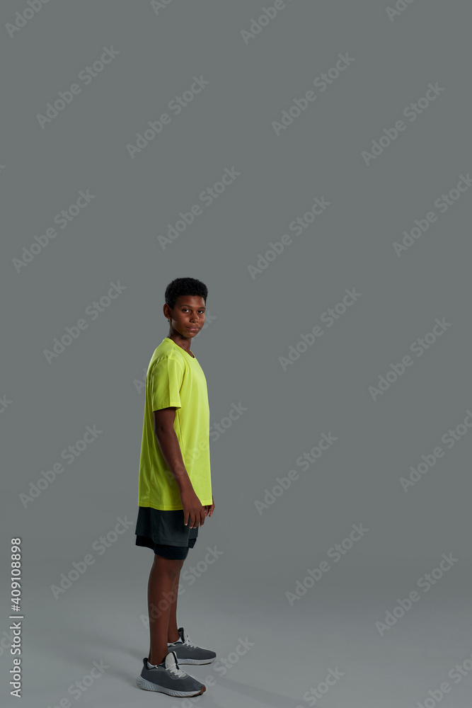Full length of a teenage african boy wearing sports clothes posing isolated over grey background in studio Full length of a teenage african boy wearing sports clothes posing isolated over grey background in studio