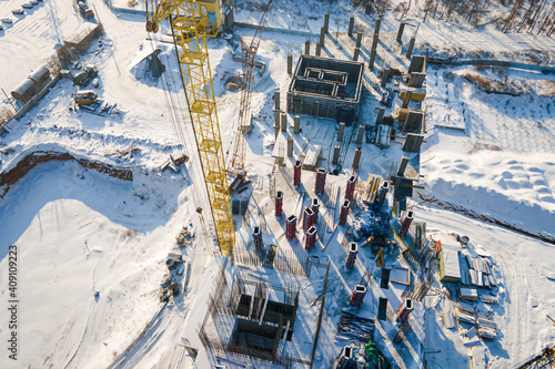 Concrete residential building in the process of construction with crane. Aerial view to the construction works on the top of concrete building. © Leonid