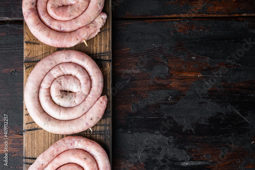 Raw snail sausage in traditional spiral, on old dark  wooden table background, top view flat lay , with space for text  copyspace