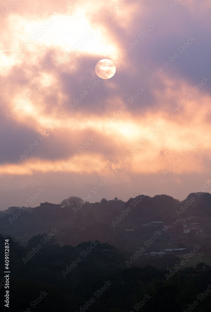 MOON OVER THE MOUNTAINS IN GOLDEN HOUR IN COSTA RICA WITH BIRDS FLYING AROUND MOON OVER THE MOUNTAINS IN GOLDEN HOUR IN COSTA RICA WITH BIRDS FLYING AROUND