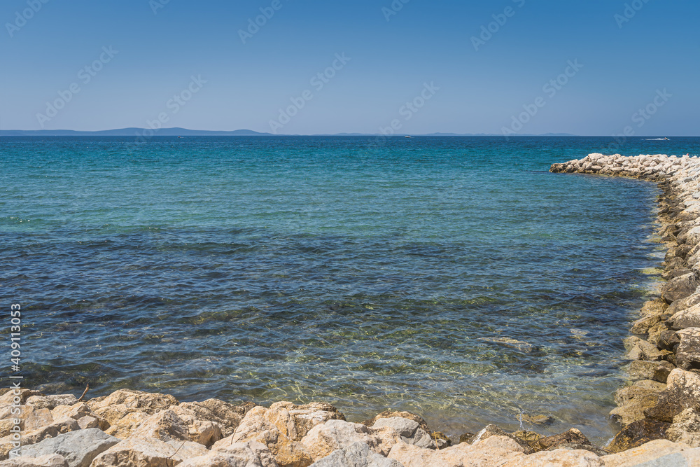 Calm, turquoise clouded and crystal clear waters of Adriatic Sea with rocky pier in Zaton bay, Croatia