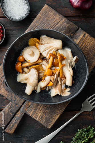 Pickled mushrooms, on old dark wooden table background, top view flat lay