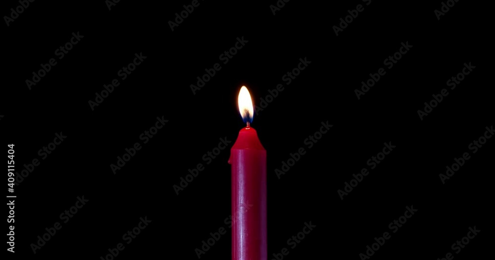 A single red candle burning. Isolated candle burning with dark background. Red paraffin candle with yellow shades burns on a black background. Background or illustration of remembrance or celebration. A single red candle burning. Isolated candle burning with dark background. Red paraffin candle with yellow shades burns on a black background. Background or illustration of remembrance or celebration.