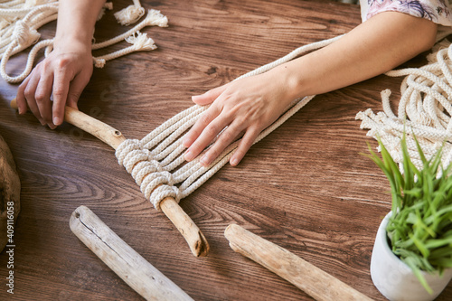 Female hands working a macrame decoration on a wooden desk
