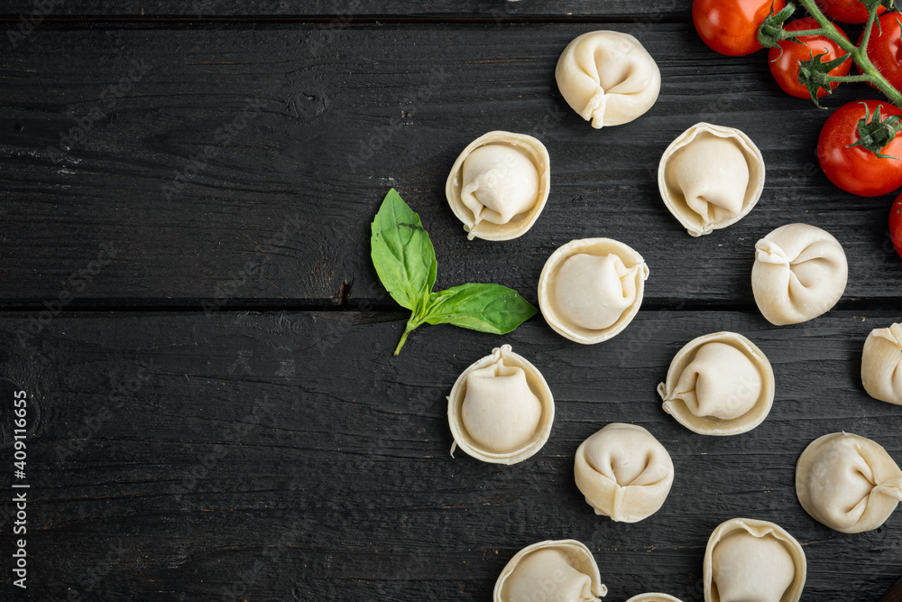 Italian tortellini with fresh ricotta leaves and tomatoes, on black wooden table background , top view flat lay , with copyspace  and space for text