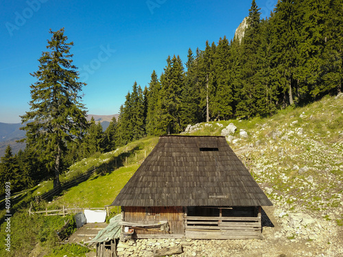 Canvas Print An abandoned wooden sheepfold in a beautiful pasture, surrounded by spruce forests