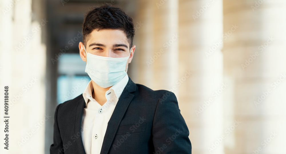 portrait of a student manager in a mask from coronavirus, pandemic, epidemic, virus. He was wearing a black business suit and a white shirt. works as a manager in a bank. the European appearance.