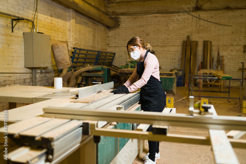 Female carpenter cutting wooden boards with a table saw