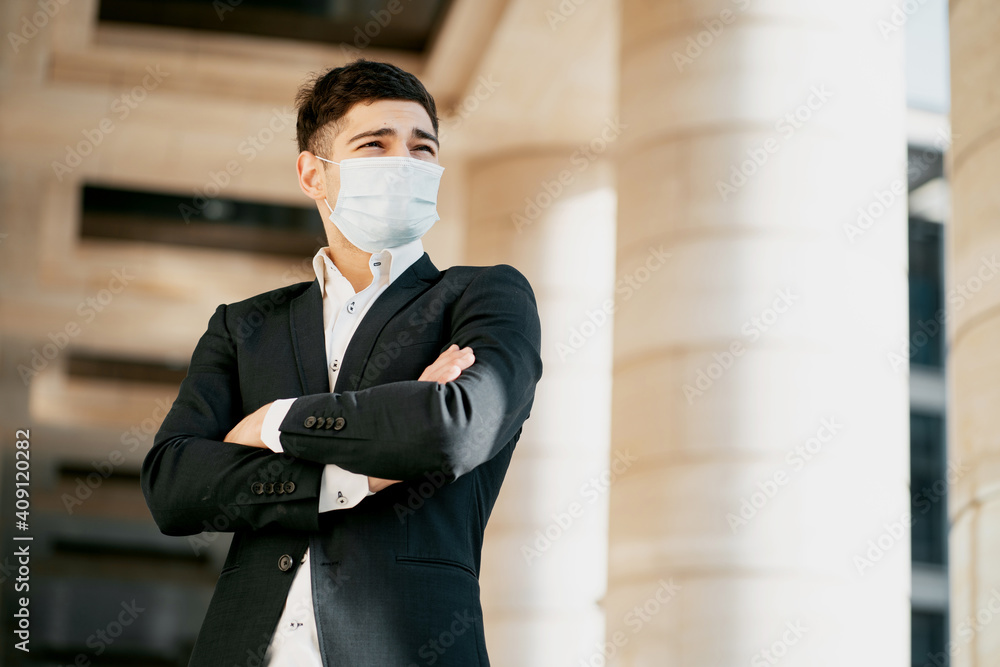 a manager wearing a coronavirus mask works at a bank. the man is dark-haired, of Italian appearance. He was wearing a black business suit and a white shirt. copy space. a manager wearing a coronavirus mask works at a bank. the man is dark-haired, of Italian appearance. He was wearing a black business suit and a white shirt. copy space.