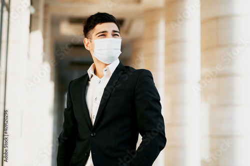 the businessman and the coronavirus wore a protective mask on his face against the virus, bacteria, microbes, infections and flu. He's standing there in a black business suit. copy space