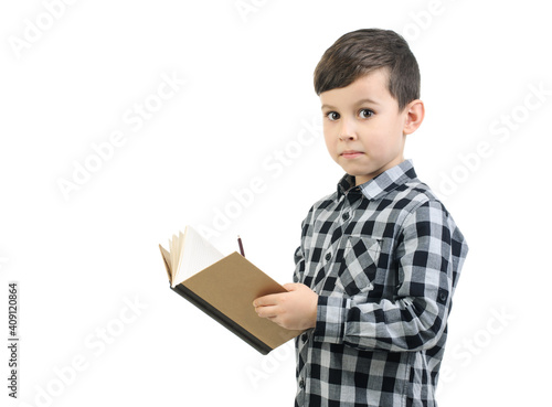 Boy 6 years old in a gray shirt writes in a notebook , Schoolboy surprised on studio white isolated background. Emotion,education