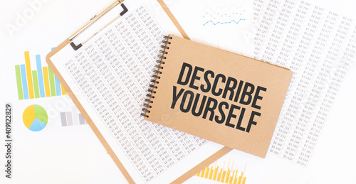 Text DESCRIBE YOURSELF on brown paper notepad on the table with diagram. Business concept