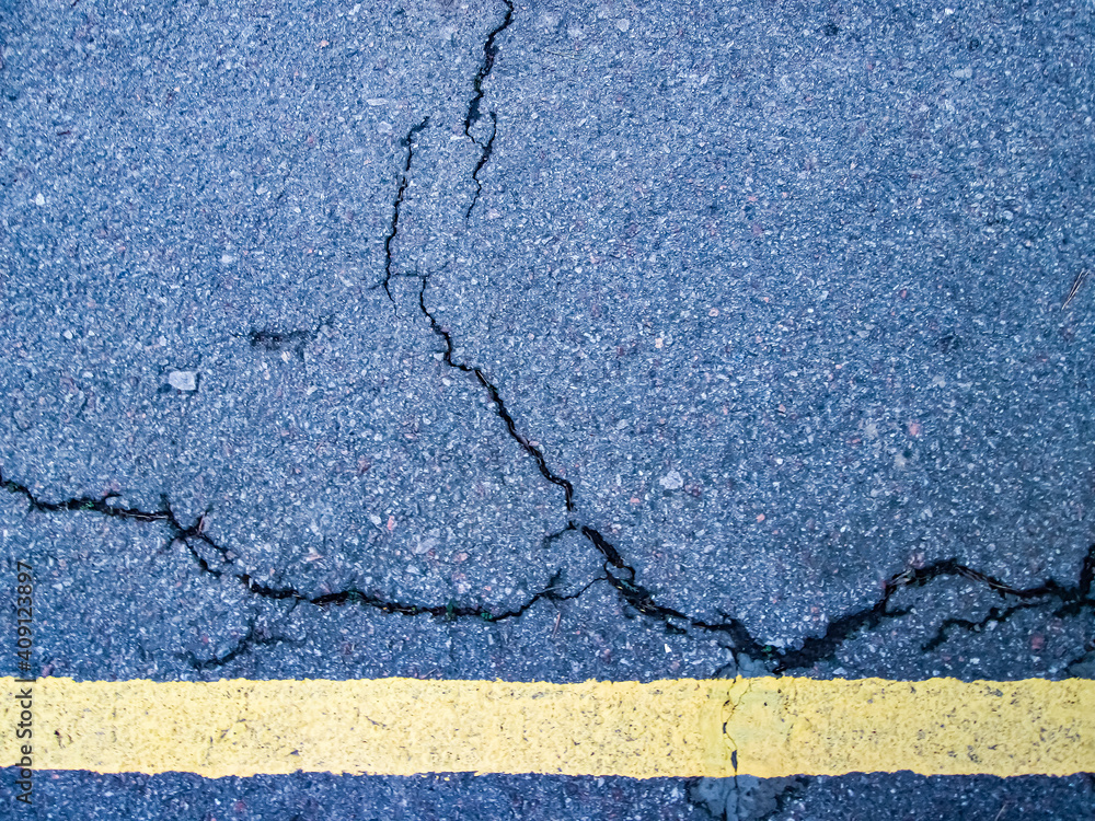 Obraz premium Yellow lane and cracked asphalt. Old markings at the stadium.