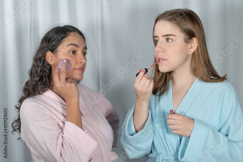 INTERRACIAL WOMEN FRIENDS DOING THEIR MAKEUP