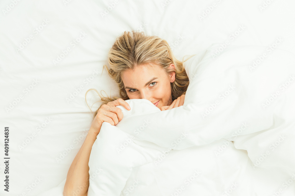 Caucasian blonde peeking from under the covers Caucasian blonde peeking from under the covers