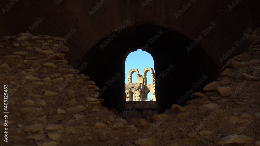 View of the internal facade of the amphitheater through a stone window. Ancient Roman ruins. Ancient amphitheater located in El Jem, Tunis. Historic Landmark.