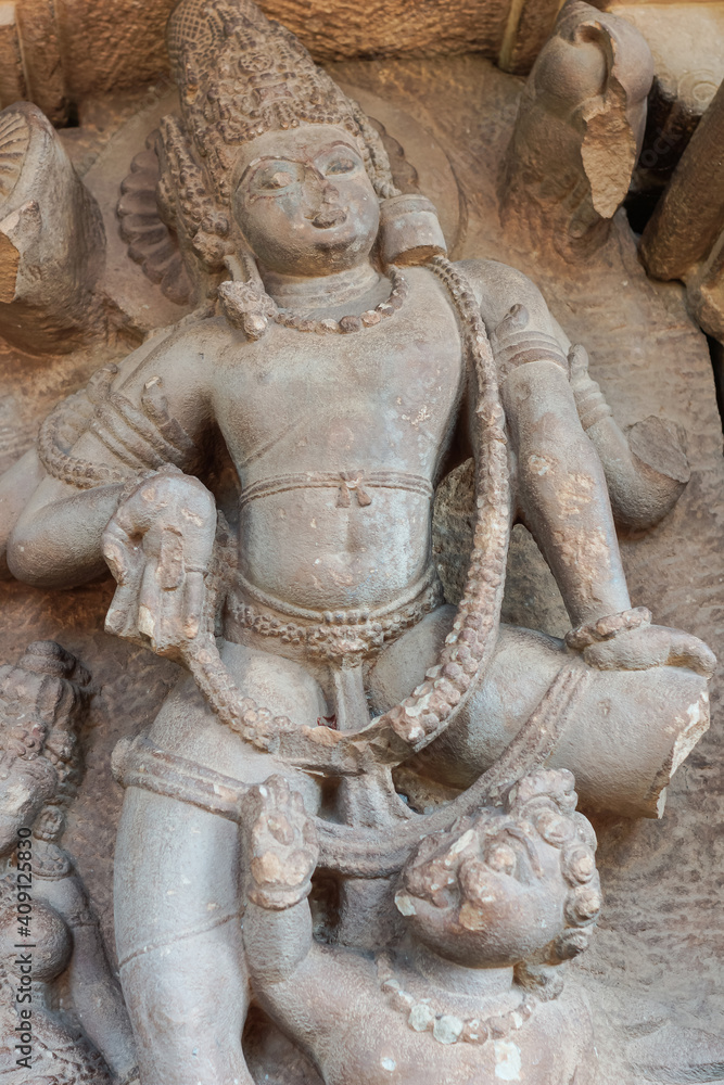 Aihole, Karnataka, India - November 7, 2013: Durga Gudi or Temple. Closeup of gray stone, heavily damaged male god statue.