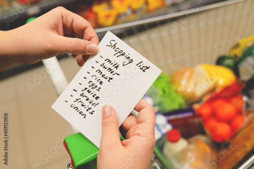 list of products in hands. supermarket with grocery cart.
