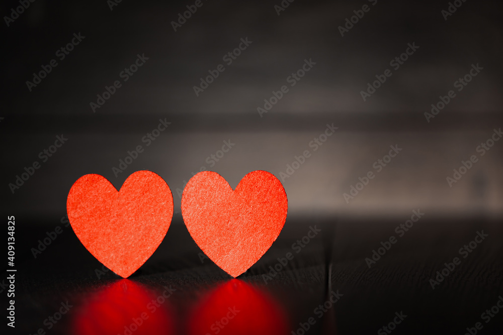 Fototapeta premium Against the background of a dark tree two red hearts, use as a background or postcard