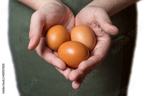 three brown chicken eggs in a man's hands on a green background