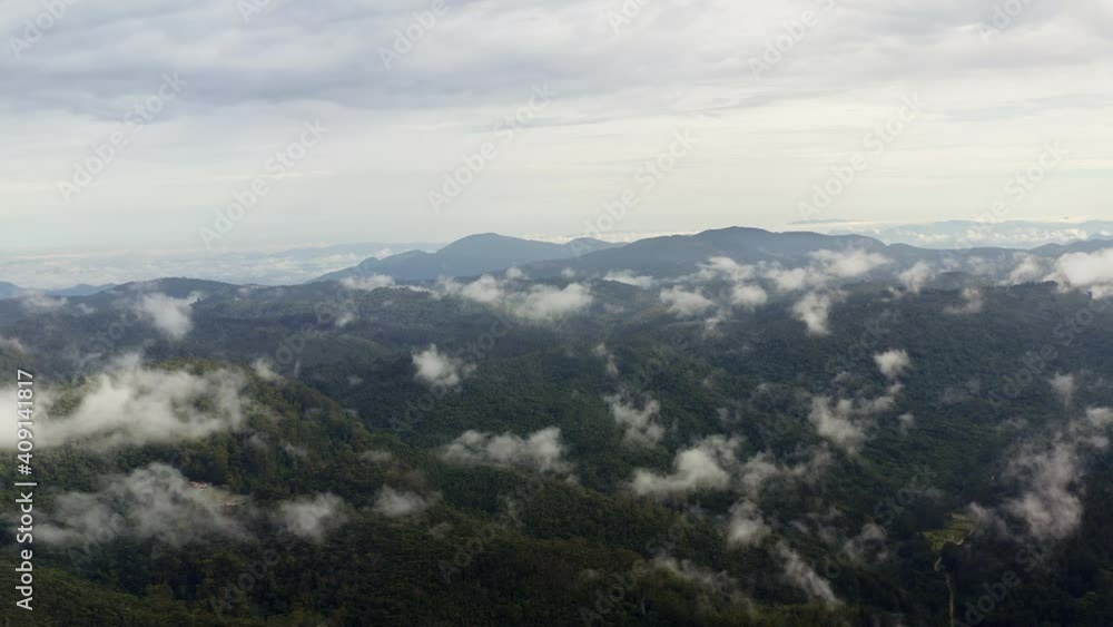Drone View of Cloudy Mountains in The Lush Morning of Green Hills Covered by Tropical Rain Clouds. The First Rays of The Rising Sun Break Through The Clouds And Hit The Tree Crowns. Drone View of Cloudy Mountains in The Lush Morning of Green Hills Covered by Tropical Rain Clouds. The First Rays of The Rising Sun Break Through The Clouds And Hit The Tree Crowns.