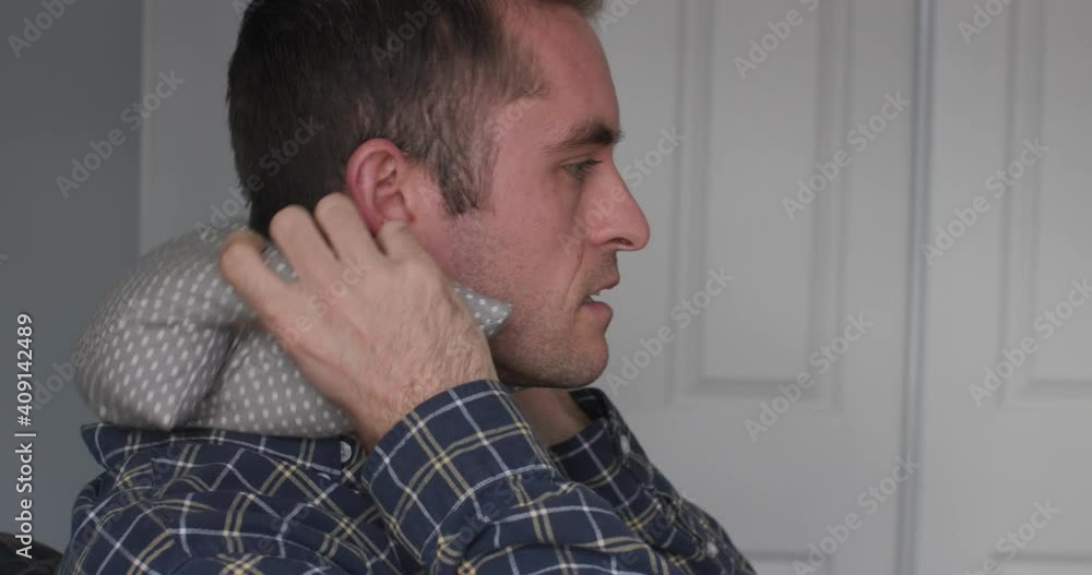 Man putting a heating pad on sore neck Man putting a heating pad on sore neck