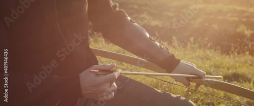 Archer man hand nock or attach and set an arrow wooden bow close up