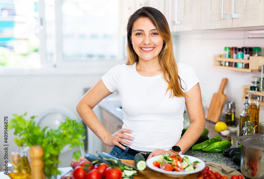 Portrait of positive woman with vegetables at kitchen top