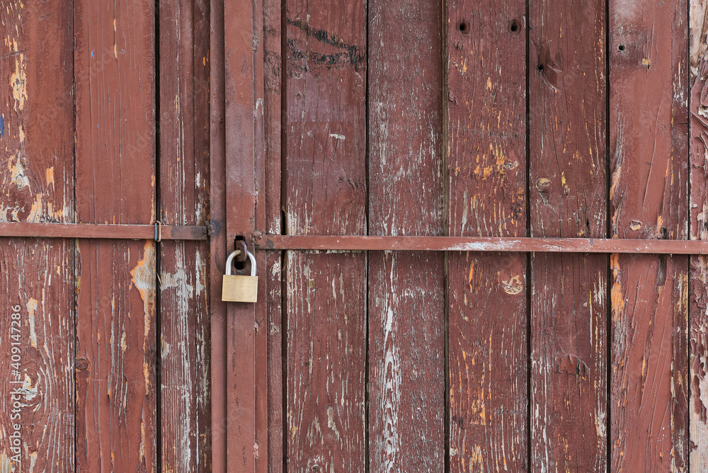 Rusty old wooden garage door painted in red with metal stel bars and padlock rural street poor neighborhood in Sofia, Bulgaria, Eastern Europe