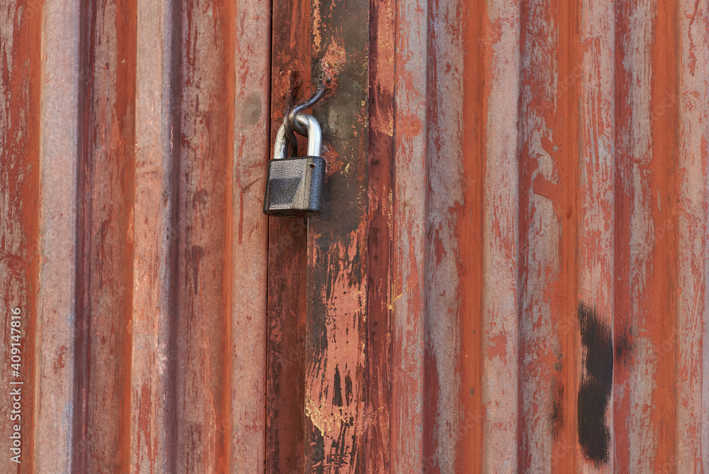 Red metal door closed on the lock corrugated steel fence gate padlock garage shed in Sofia, Bulgaria, Eastern Europe Red metal door closed on the lock corrugated steel fence gate padlock garage shed in Sofia, Bulgaria, Eastern Europe