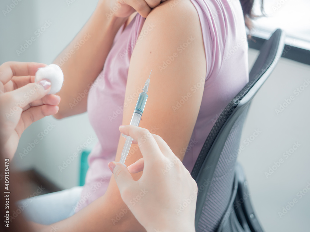 hand of a doctor holding vaccine Syringe. Persons administering vaccinations, doctor use hand cleansed with an alcohol-based giving vaccine injection to a patient. hand of a doctor holding vaccine Syringe. Persons administering vaccinations, doctor use hand cleansed with an alcohol-based giving vaccine injection to a patient.
