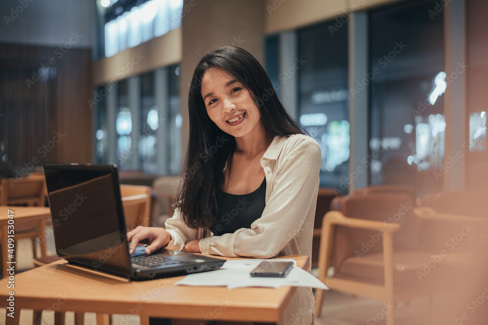 Young woman working on laptop at night. businesswoman smiling and working in office at night.