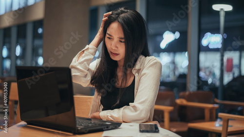 Serious woman working on laptop late at night. Asian Businesswoman working hard and overtime in office.