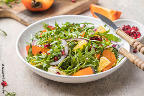 Delicious persimmon salad with arugula and orange served on light grey table, flat lay. Space for text