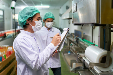 Asian factory workers were checking list with chart to safety policy on automatic machine in beverage industry