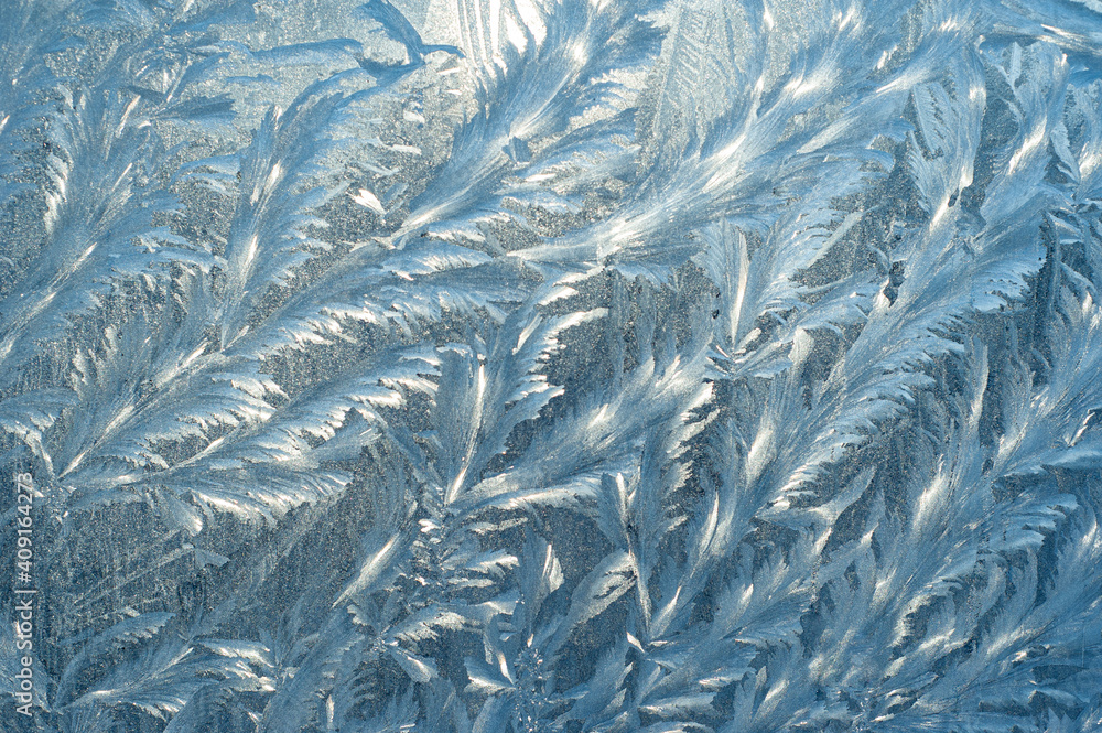 Frosty patterns on the window at dawn. Frosty window texture. Abstract background.