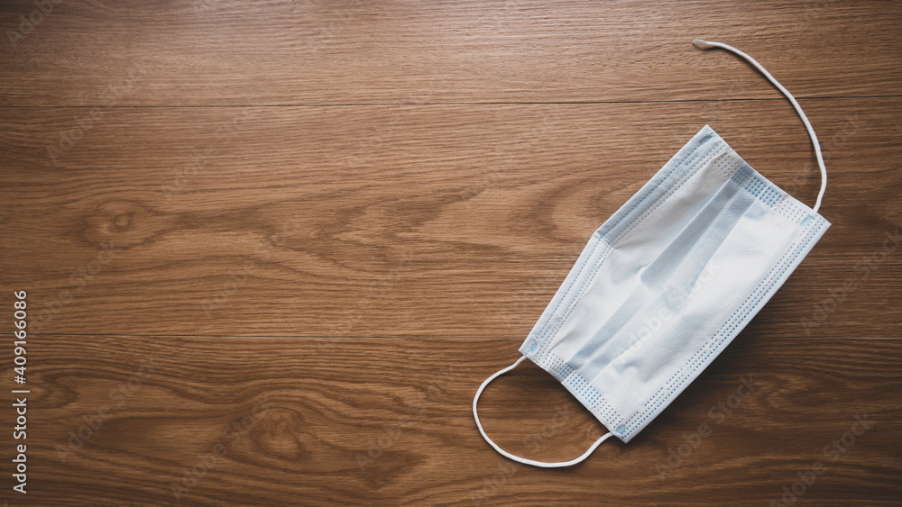 Selective focus of used and broken face mask on the wooden floor with copy space.