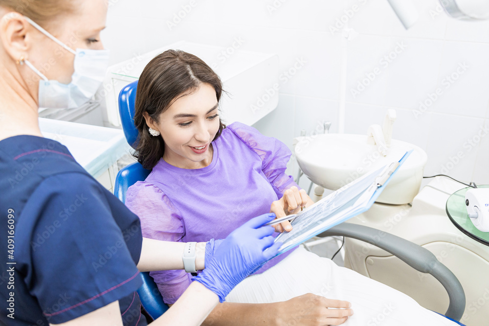 Dentistry concept. Professional dental services and modern equipment without pain. The doctor consults and treats the young woman, conducts an examination and draws up a treatment plan Dentistry concept. Professional dental services and modern equipment without pain. The doctor consults and treats the young woman, conducts an examination and draws up a treatment plan