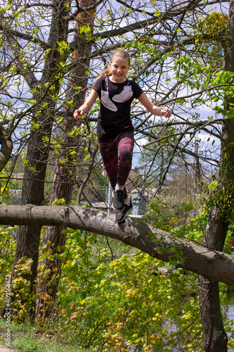 teenager jumping from a broken tree on a forest path in spring