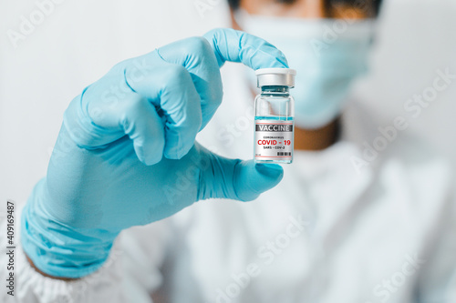 Virus protection concept The doctor's hand held a transparent ampoule of liquid for injection, a clear vial filled with antiviral medicine.