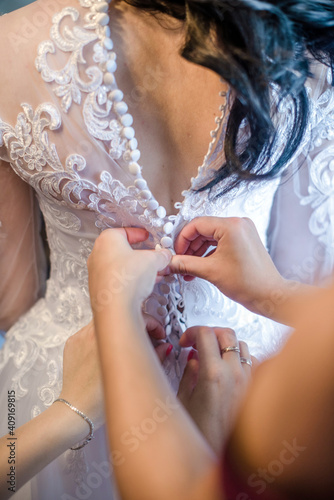 The girl fastens the white dress of the bride 