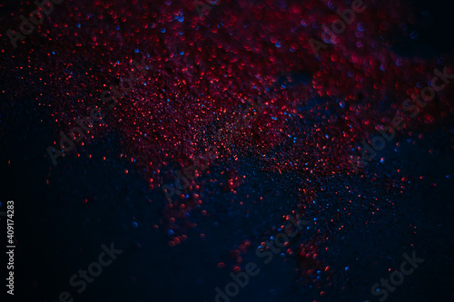 Red sand from sequins. Scattered sparkles on a black background. Space texture. Stars